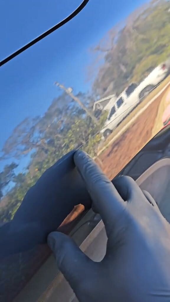 Gloved hand on dark paint reflecting the sky like a mirror